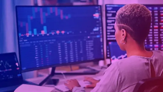 Woman sitting at computer looking at financial graphs